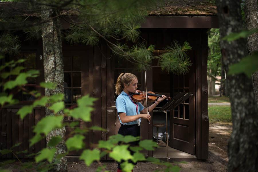 violinist practices outside practice cabin at interlochen arts camp