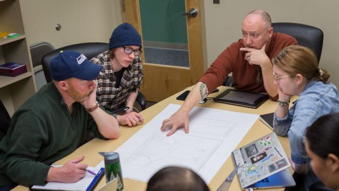 Stephen John (top right) explains his class's set design for As You Like It to Instructor of Theatre Andy McGinn (bottom left).